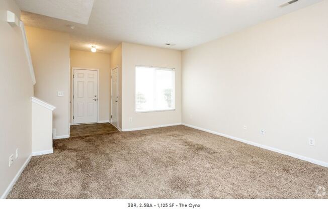 an empty living room with carpet and a white door