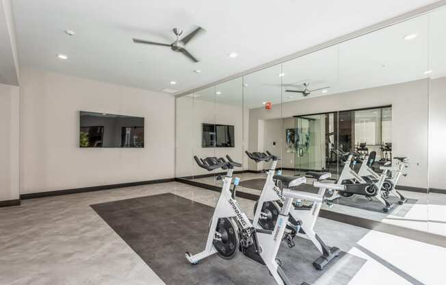 a gym with treadmills and other exercise equipment in a glass walled room