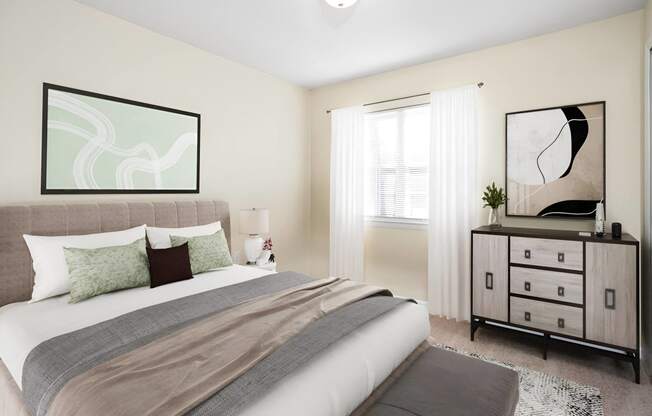 a bedroom with a bed and a dresser at West Pointe Apartments in Burlington, NC