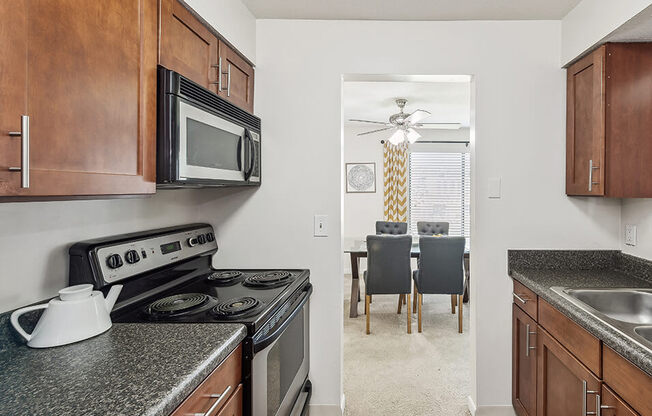 a kitchen with a stove and microwave and a dining room