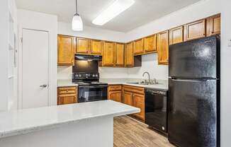 A kitchen with wooden cabinets and black appliances.