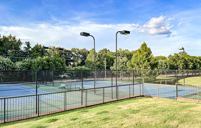 a tennis court with a fenced in area and a blue court in the background