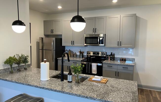 a kitchen with gray cabinets and a granite counter top