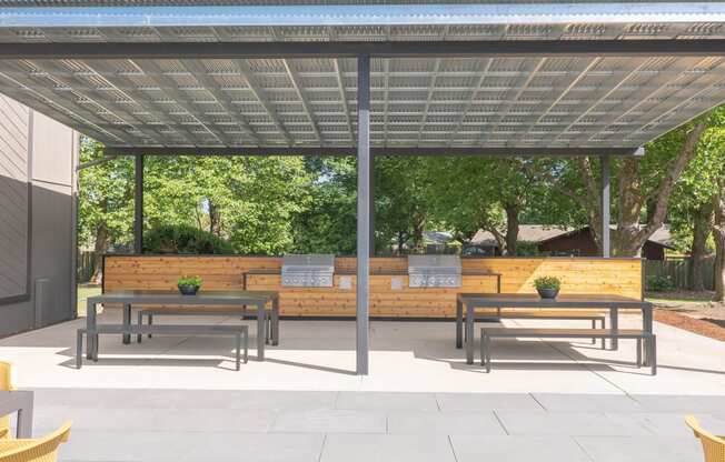 a large pergola with benches and tables under it