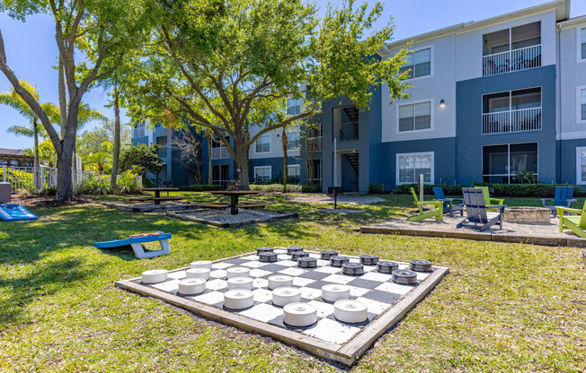 a large chess board in the middle of a grassy area with an apartment building in the