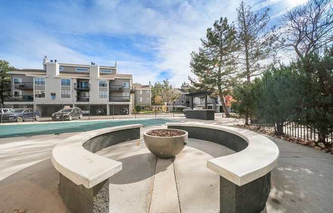A circular concrete bench with a planter in the middle is surrounded by a concrete walkway.