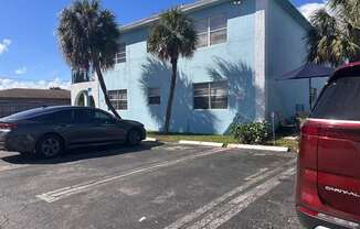 A car is parked in a parking lot in front of a blue building.