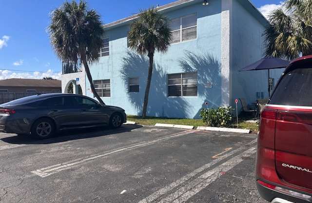 A car is parked in a parking lot in front of a blue building.