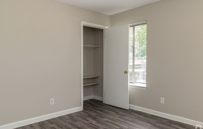 an empty bedroom with a closet and a window