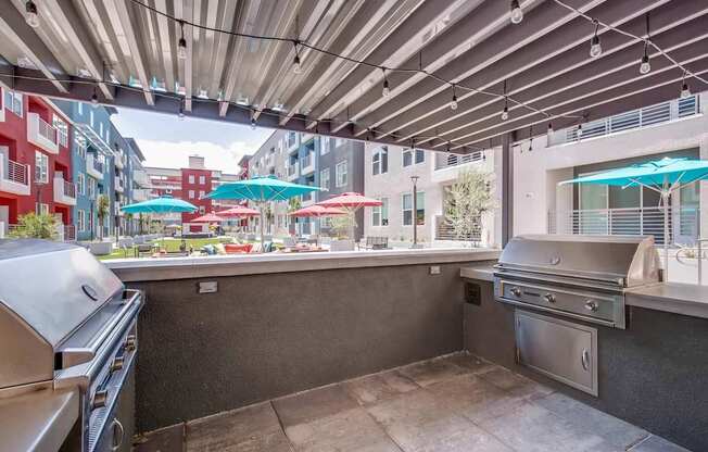A patio with a grill and umbrellas.