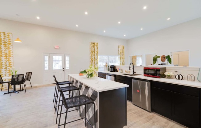 a kitchen with a long counter and black and white chairs at Station JTown, Kentucky, 40299