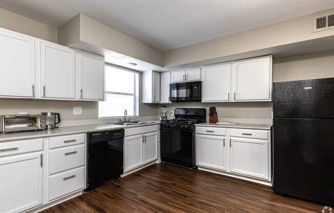 A kitchen with black appliances and white cabinets.