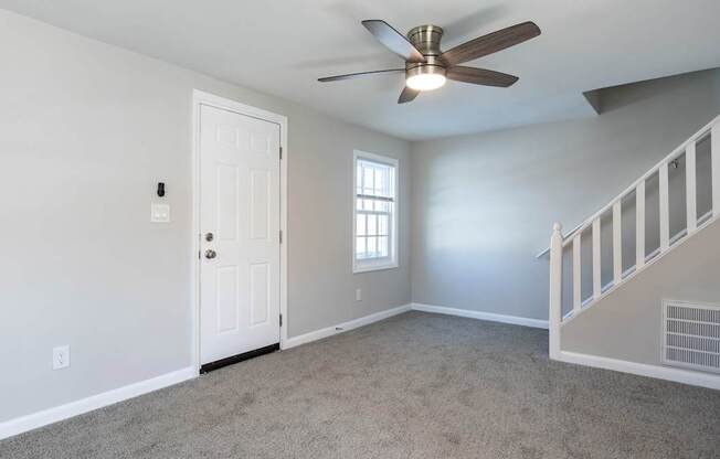 A room with a ceiling fan and a staircase.