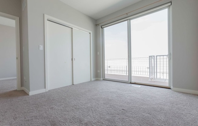 an empty bedroom with large windows and a balcony
