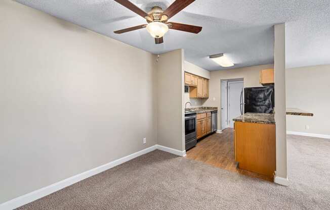 a bedroom with a ceiling fan and a kitchen in the background