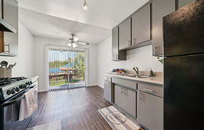 A kitchen with a black refrigerator and wooden floors.