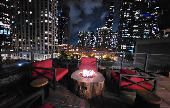 A fire pit sits in the middle of a wooden table on a rooftop patio.