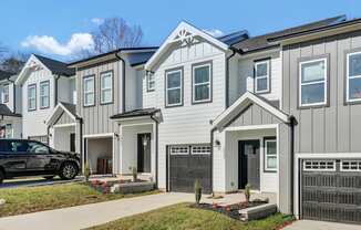 a row of white homes with a black car parked in front