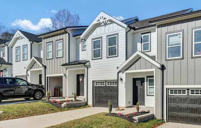 a row of white homes with a black car parked in front