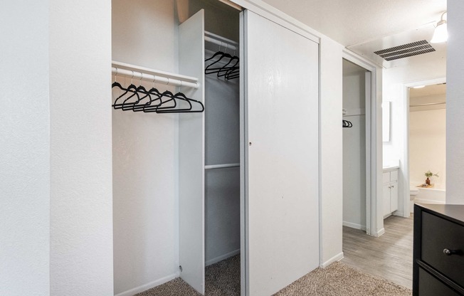 a walk in closet in a bedroom with a mirrored closet door