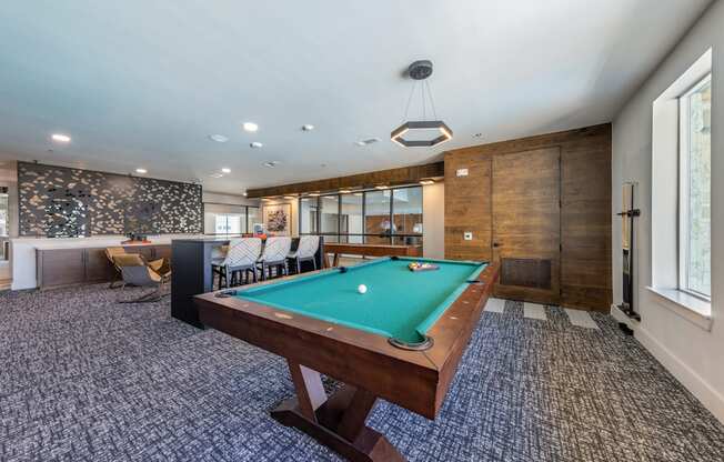 A pool table is in the middle of a room with a patterned carpet.