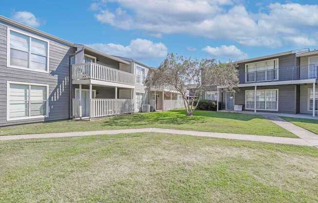 A sunny day at the apartment complex with apartment buildings on the left and right and a walkway in front at Maplewood apartments in Shreveport, LA.