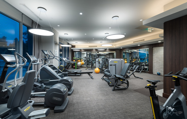 Treadmills, ellipticals, stair climbers, and weight machines in the gym.