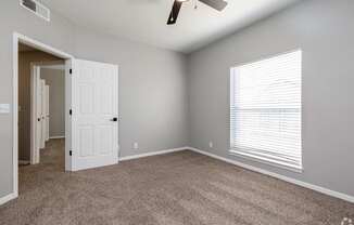 A room with a carpeted floor and a ceiling fan.