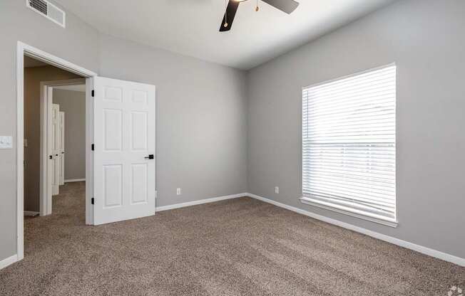 A room with a carpeted floor and a ceiling fan.