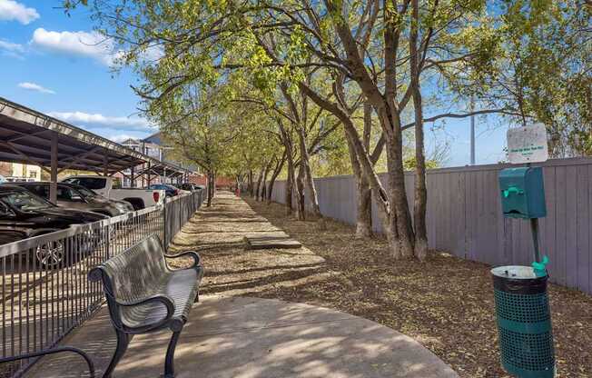 A park with a bench and a trash can.
