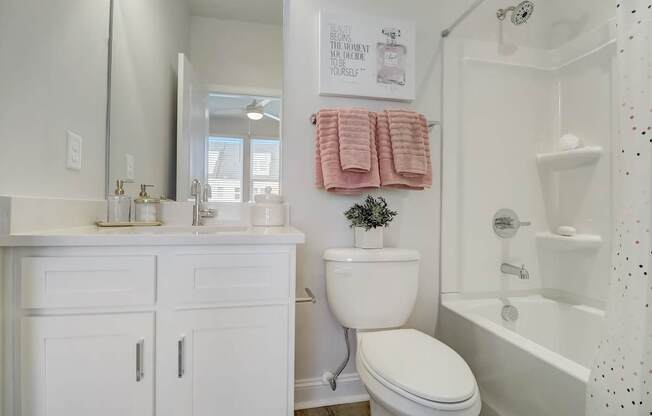 A white bathroom with a toilet, sink, and bathtub.