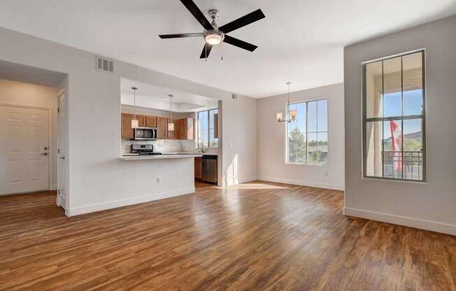 A spacious living room with a ceiling fan and hardwood floors.