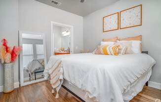 A bedroom with a white bed and orange pillows.