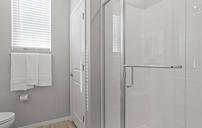 a white bathroom with a glass shower and a white toilet