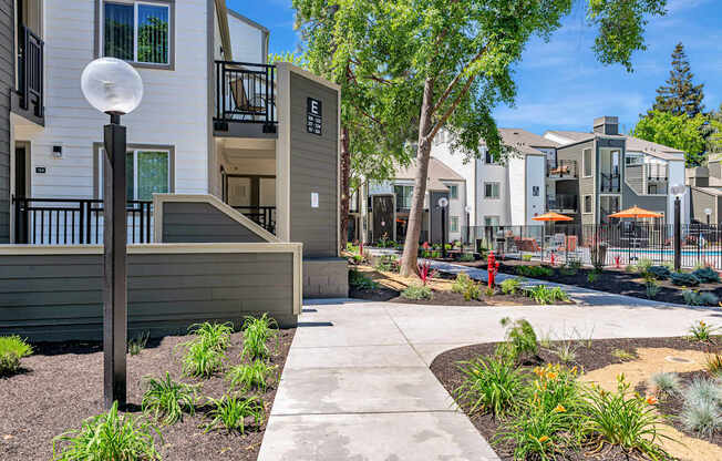 A modern apartment complex with a well-maintained garden in the foreground.