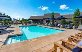 our resort style swimming pool is surrounded by lounge chairs and umbrellas