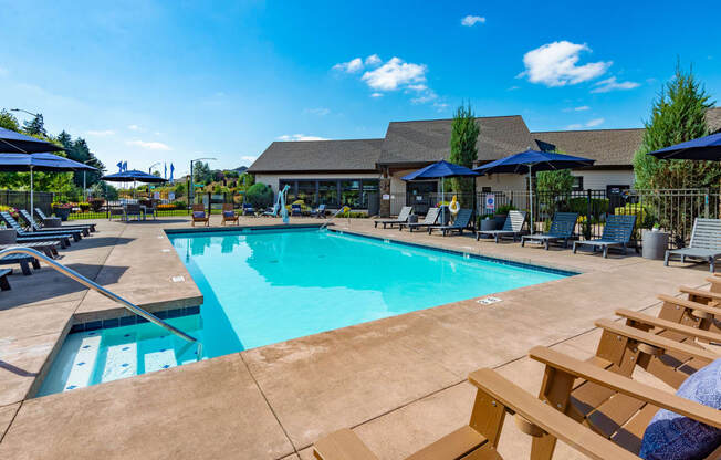 our resort style swimming pool is surrounded by lounge chairs and umbrellas