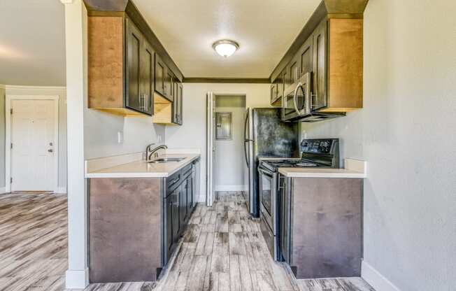 an empty kitchen with stainless steel appliances and wood flooring