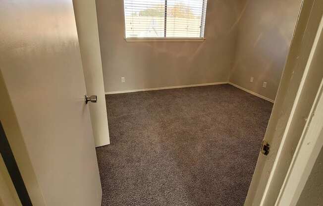 an empty room with a ceiling fan and a window