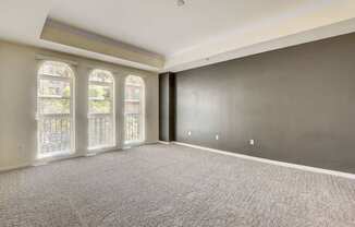 A spacious room with grey carpeting and large windows.