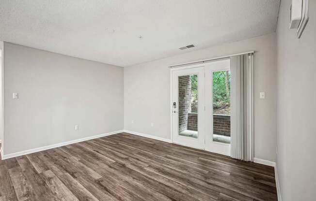 A room with a sliding glass door and wood flooring.