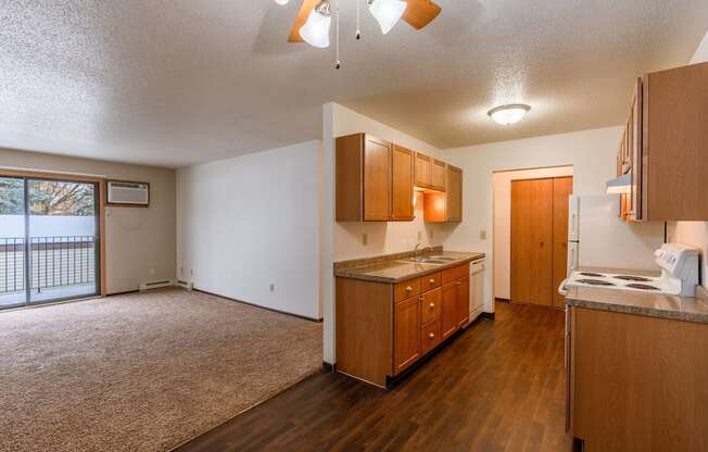 A kitchen and living room with a door to a balcony. Fargo, ND Long Island Apartments.