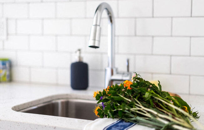 a kitchen sink with a bunch of flowers on the counter