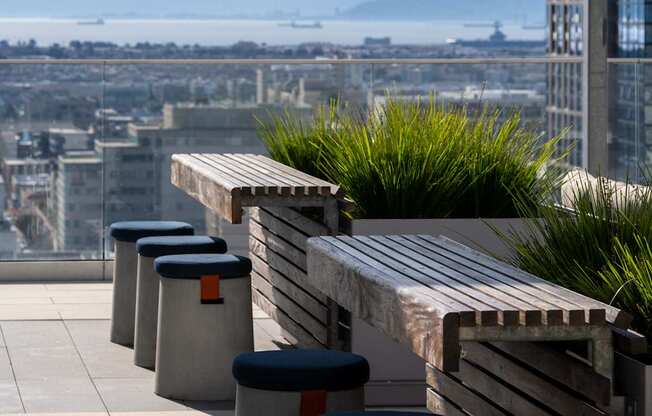 A row of grey concrete bins with black lids are lined up on a rooftop terrace.