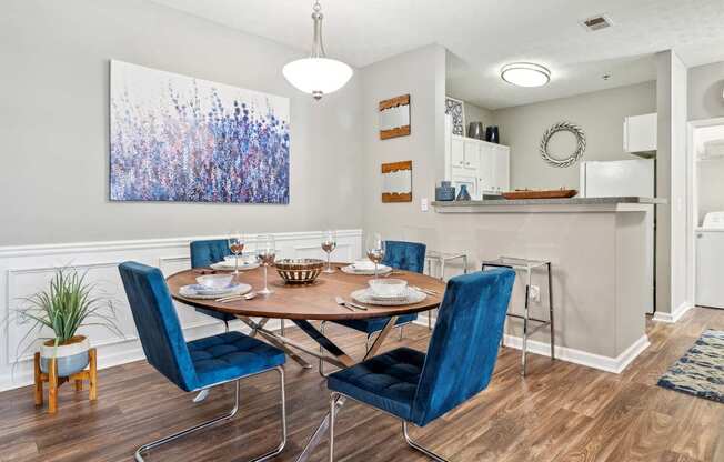 A dining room with a table set for two and a large abstract painting on the wall.