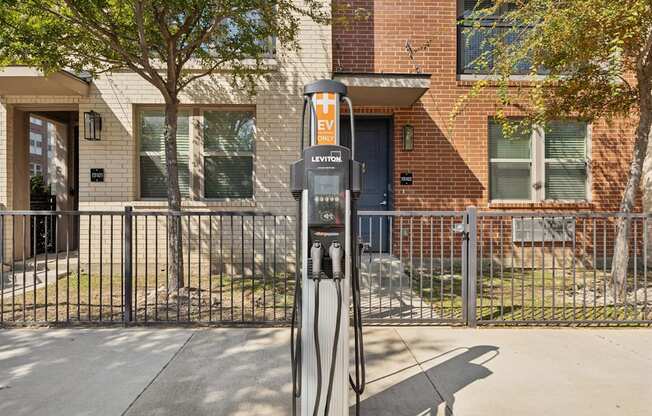 A brick building with a black fence and a charging station in front.