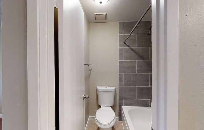 Modern bathroom with sleek gray tiles and a pristine white bathtub, creating a refreshing and contemporary space.