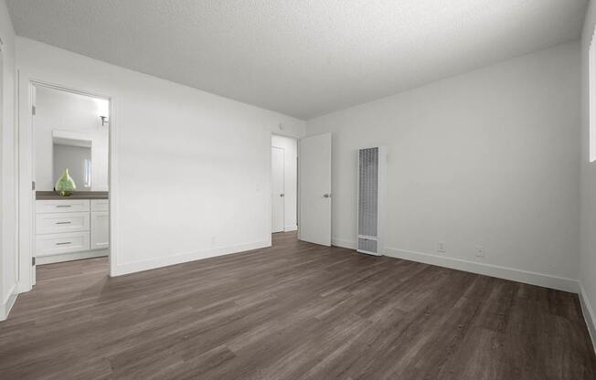 A room with wooden flooring and white walls.