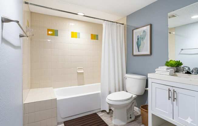 A white bathtub with a shower head and a white toilet in a bathroom.
