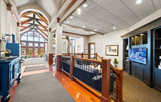 A large room with a balcony and a TV on the wall.